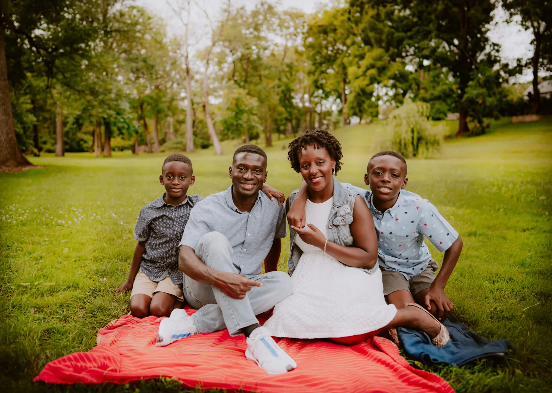 A Black family sitting together outdoors in a park
